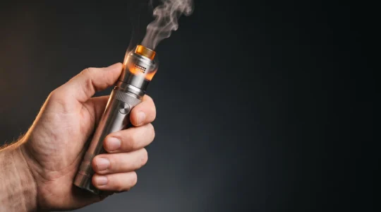 Vapoteur tenant une box mod avec atomiseur reconstructible, ambiance chaleureuse évoquant la maîtrise de la chauffe